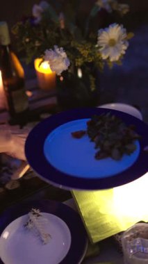 Büyüleyici bir yemek sahnesi. Güzel düzenlenmiş tabaklar, titreyen mumlar ve canlı çiçekler.