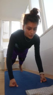 Genç bir kadın dinamik yoga pozları veriyor, esnekliğini gösteriyor ve parlak, davetkar bir yere odaklanıyor.