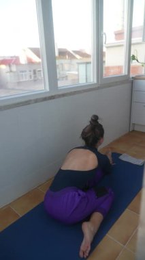 Yoga pratisyeni, sükuneti teşvik eden parlak ve sakin bir alanda derin, tatmin edici bir gerinme gerçekleştirir.