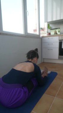 Kendini yogaya adamış bir kişi, çeşitli hareketlerle esnekliği ve rahatlığı arttırarak evde yoga yapar ve poz verir.