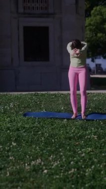 Etrafı güzel, yemyeşil yeşilliklerle çevrili mavi bir minder üzerinde yoga yapan odaklanmış bir birey.