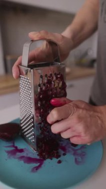 Güzel bir deniz mavisi kesme tahtasının üzerinde taze pancar kökü rendeleyen birinin yakından görüntüsü.