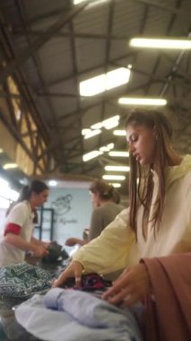 Genç bir kadın alışverişe dalmış renkli kumaşları ve çantaları dikkatle inceliyor.