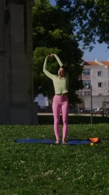 Güneşli bir parkta çeşitli yoga hareketleri yapan bir kadın sağlık ve sağlığın önemini vurguluyor.