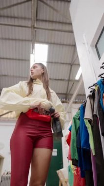 Şık bir insan şık bir ucuzluk mağazasında renkli kıyafetlere bakıp hareketli atmosferin tadını çıkarıyor.