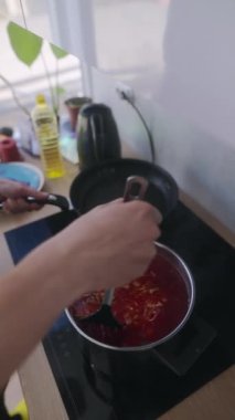 Canlı bir domates sosu sıcak bir sobanın üzerinde kaynıyor, parlak ve davetkar bir mutfak atmosferini vurguluyor.