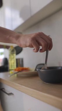 Bir birey, modern bir mutfakta taze malzeme ve aletleri ustalıkla harmanlayarak enfes bir yemek hazırlar.