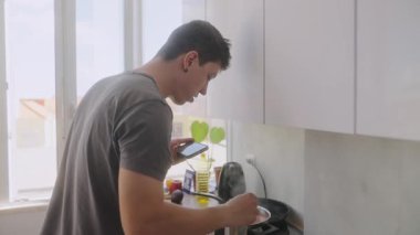 Genç bir adam açık, modern bir mutfakta yemek pişirirken lezzetli ve lezzetli bir yemeğin tadına bakıyor.