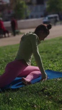 Güzel ve canlı bir park ortamında, genç bir kadın ustaca yoga pozları veriyor.