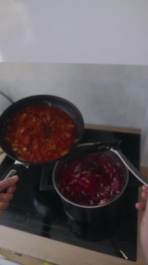 Yemek hazırlama sürecindeki detaylı bir adım. Malzemelerin sobadaki kaba dikkatlice eklendiğini gösteriyor.