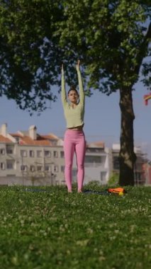 Neşeli bir kadın güzel güneşli bir parkta vücudunu mutlu bir şekilde gerer, pozitif enerji ve canlılık saçar.