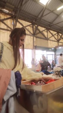 Bir insan renkli kıyafetleri ve çeşitli aksesuarları kolay bir şekilde gözden geçirir.