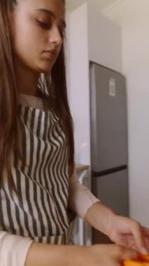 Şık, çağdaş bir mutfakta, genç bir insan ustalıkla taze, canlı havuçları ustalıkla hazırlar.