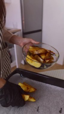 Modern mutfak ortamında altın sarısı fırınlanmış patates dilimlerini ustalıkla hazırlayan bir insan.