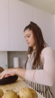 Genç bir kadın şık bir mutfakta sebze hazırlıyor, aşçılık becerileri ve taze malzemeler sergiliyor..