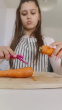 Genç bir kız, modern mutfak ortamında etkileyici mutfak becerilerini sergileyerek taze havuç soyuyordu.