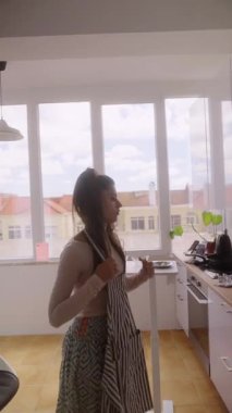 Modern bir aşçı parlak bir mutfakta renkli bir önlük giyer. Lezzetli yemekler yapmaya hazırdır.