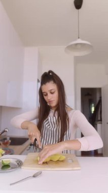 Şık ve modern bir mutfak ortamında ustalıkla ve ustalıkla taze, canlı ürünleri dilimleyen bir kadın.