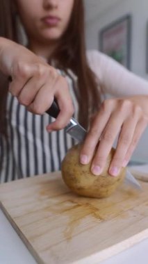 Bir insan ustalıkla patates soyar ve doğrar, mutfak teknikleri ve taze malzemeler sergiler..