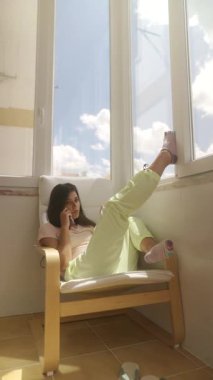 Bir sandalyede rahat bir şekilde uzanan ve güzel bir pencerenin yanında huzurlu bir anın tadını çıkaran bir insan.