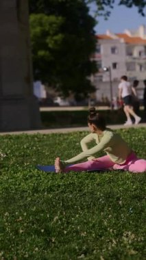 Bir kadın zarif bir şekilde sakin bir parkta esneyerek olağanüstü esnekliğini ve iç huzurunu sergiliyor.