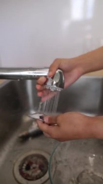 Çalışkan bir insan, modern bir mutfak musluğunun altında parlak paslanmaz çelik bir lavaboda taze balık duruluyor.