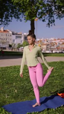 Genç bir kadın zarif bir şekilde yoga yapıyor açık havada poz veriyor, açık havada, esneklik ve denge gösteriyor..