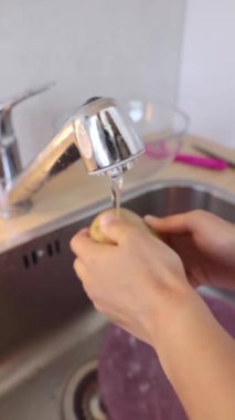 Mutfak lavabosunda patatesi özenle yıkayan biri yemek pişirmek için hazırlıyor.