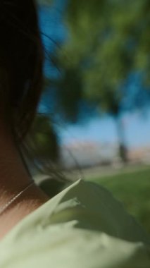 Genç bir kadın güzel bir parkta huzur içinde oturuyor. Çevresindeki yeşillik ve sıcak güneş ışığına dalmış.