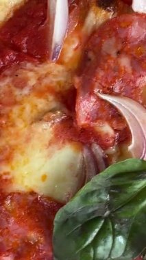 Taze fesleğen ve domates sosuyla kaplı ağız sulandıran pepperonili pizzanın tadını çıkarın.