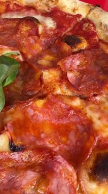 Ekstra lezzet vermesi için taze fesleğen yapraklı klasik pepperonili pizzanın tadını çıkarın.