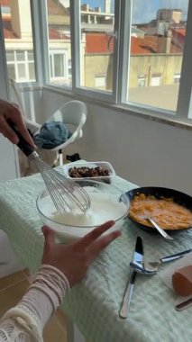 Lezzetli bir yemek hazırlarken birinin özenle kremalı malzemelerini çırptığı sıcak ve rahat bir mutfak.