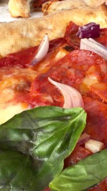 Lezzetli malzemeler ve taze fesleğenle kaplanmış taze yapılmış pizzaya bakın.