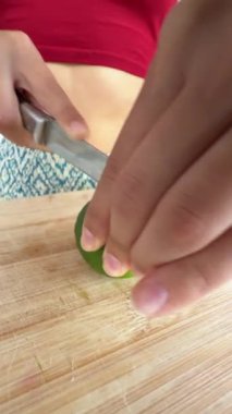 Bir insan ahşap bir tahtada ustalıkla taze limon keser, canlı renkler ve yemek pişirme inceliği sergiler..