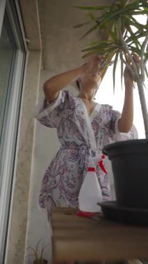 Rahat bir bornoz giymiş bir kadın bitkileriyle ilgileniyor, dingin ve huzur verici bir atmosfer yaratıyor.