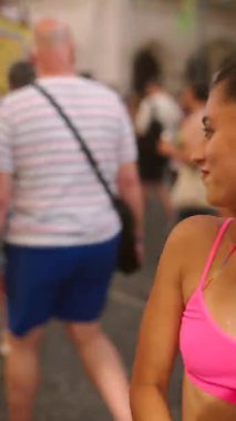 Canlı bir cadde renkli kıyafetlerle doludur ve insanlar şenlikli atmosferin keyfini çıkarırlar.