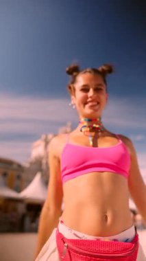 Parlak pembe elbiseli genç bir kadın neşeli ve enerjik bir yaz festivalinde dans ediyor.