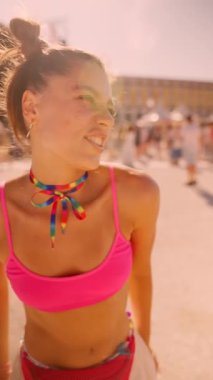 A lively festival atmosphere featuring a young woman wearing a pink outfit and colorful accessories.