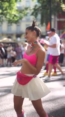 Pembe kıyafetli canlı bir dansçı, renkli bir kutlamada neşe ve özgürlüğü somutlaştıran bir geçit töreninde parlıyor.