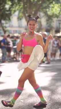 Canlı bir festival sahnesinde parlak giyinmiş, neşe saçan ve herkesi büyüleyen bir dansçı görülüyor.