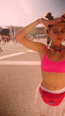 Canlı ve canlı bir festival sahnesinde neşeli aksesuarlarla birlikte pembe elbiseli neşeli bir kız sergileniyor.