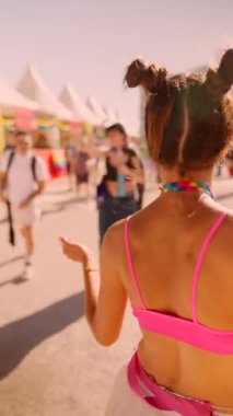 At a colorful festival, a cheerful girl in a bright outfit enjoys the lively atmosphere and joyful energy around her