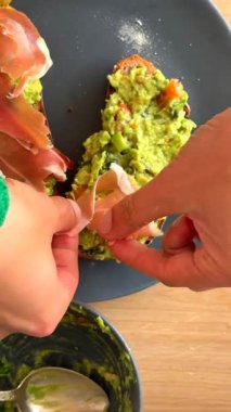 Renkli ve canlı bir avokado tostu, zarif bir şekilde dilimlenmiş prosciutto ile hazırlandı.