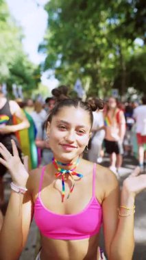 Canlı pembe elbiseli genç bir kadın gür ağaçların altında arkadaşlarıyla neşeli bir festivalin tadını çıkarıyor.