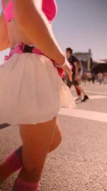 Dinamik bir sahnede enerjik hareketler yaparken canlı yaz modasını coşkuyla sergileyen bir dansçı vardır.