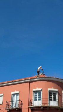 Çatı katında çalışkan bir işçi güneşli ve aydınlık bir günde gerekli temizlik görevlerini yerine getiriyor.