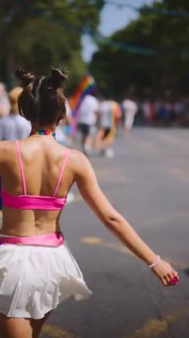 Renkli bir kıyafetin içinde neşeli bir katılımcı, bir Onur Yürüyüşü kutlamasının canlı atmosferinin tadını çıkarıyor.