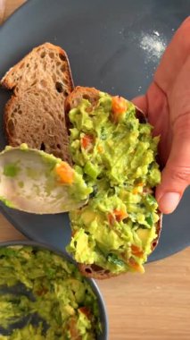 Lezzetli bir yemek için taze tahıllı ekmeğin üzerine katılmış lezzetli avokado sosunu izleyin.