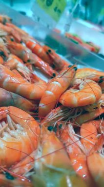 Taze karidesin yakın plan görüntüsü canlı renklerini ve dokusunu hareketli bir deniz ürünleri pazarında sergiliyor..