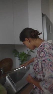 Bir kadın aktif olarak mutfak aletlerini temizleme sürecinde, sıcak bir ortam ve bakım sergiliyor.